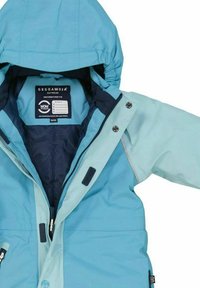 Ljusblå vattentät jacka med huva, har dragkedja fram, tryckknappsstängning och justerbara ärmslut. Inuti visas varumärkets etikett.