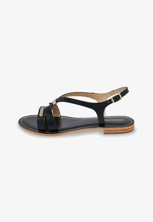 Sandale en cuir noir avec des brides croisées, un petit talon et une boucle dorée. La semelle est de couleur bois clair avec des coutures visibles.