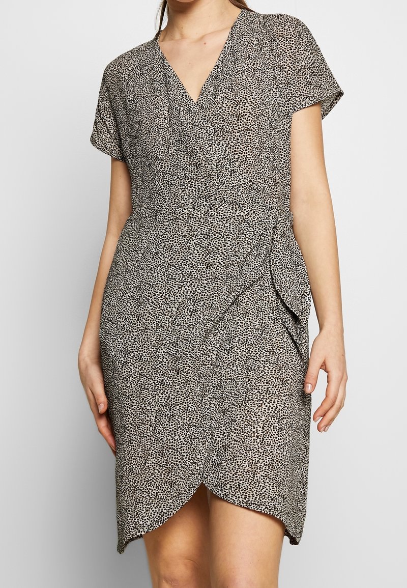 Robe portefeuille à motif à pois noir et blanc, dotée d'un décolleté en V, de manches courtes et d'un ourlet arrondi avec des détails froncés à la taille.