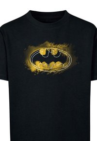 Camiseta de algodón negra con un gran logo estilizado de Batman en amarillo y acentos texturizados en la parte frontal, cuello redondo y mangas cortas.