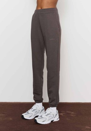 Hallid puuvillased dressipüksid elastse vöökohtadega ja kitsenevate jalgadega. Omavad küljetaskuid ja diskreetset logo vasakul küljel.