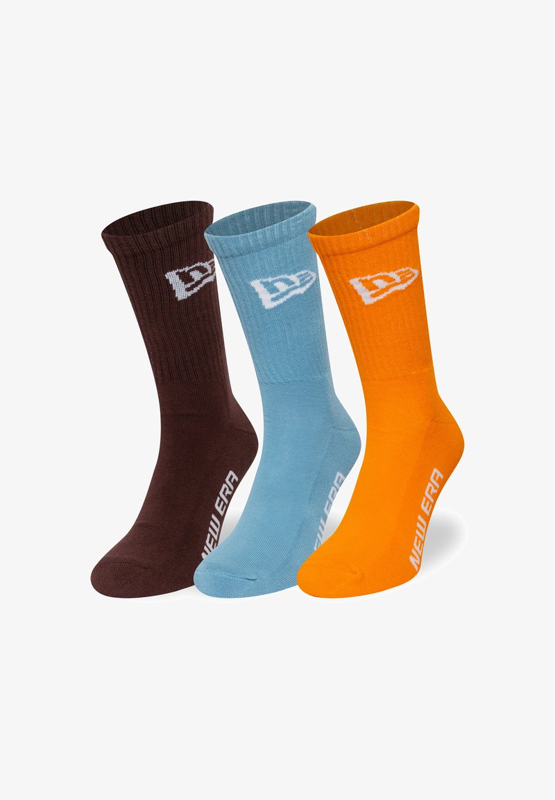 Trīs zeķu pāri: brūnas, gaiši zilas un oranžas. Katrs ar baltu logo. Ribotā tekstūra un plaukta garuma dizains.