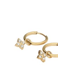 Orecchini a cerchio in tono oro con un charm a forma di fiore, decorato con quattro strass trasparenti. Finitura in metallo liscia e dal aspetto lucido.