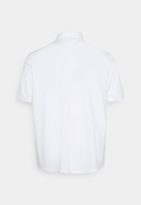 Polo blanc uni à manches courtes montré de dos avec un col classique et un ourlet droit.