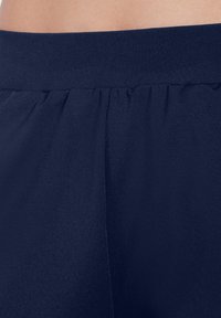Tela elástica de color azul marino con una textura suave, presenta una cinturilla elástica y un detalle fruncido en la parte superior. Diseño sencillo y minimalista.