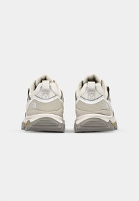Gray and white trail shoes with a textured upper, padded collar, and a rugged outsole. Features a pull tab at the heel and a logo on the side.