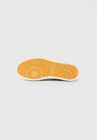 Σόλα παπουτσιού σε ανοιχτό καφέ χρώμα με υφή αυλακώσεων, κυκλικό σχέδιο λαβής και χαραγμένο το λογότυπο "GANT" στο κέντρο.