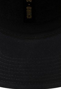 Schwarzer Bucket Hat aus strapazierfähigem Stoff, mit glatter Textur und subtilen Nähdetails. Das Innenetikett trägt die Aufschrift "Ichiro 2023."