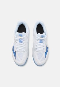 Baskets de sport blanches avec des accents bleus, panneaux en mesh texturé, design à lacets et col rembourré. Logo réfléchissant sur la languette.
