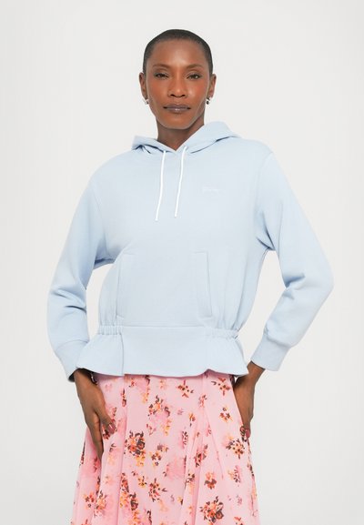 Light blue hooded sweatshirt with a peplum waist, large front pockets, and white drawstrings, paired with a pink floral skirt.
