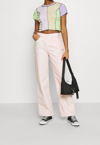 Colorful cropped top with various stripes, paired with pink checkered wide-leg pants. Black bag and sneakers complete the outfit.