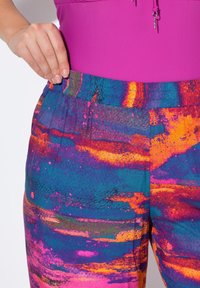 Kleurige, gedessineerde broek met een brede elastische tailleband, voorzien van een mix van blauwe, paarse, oranje en roze abstracte ontwerpen. Glad materiaal.