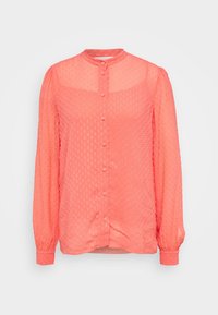 Blusa lunga a maniche con polsini arricciati di colore corallo rosa, con motivo a pois testurizzati, chiusura con bottoni sul davanti e colletto a band. 