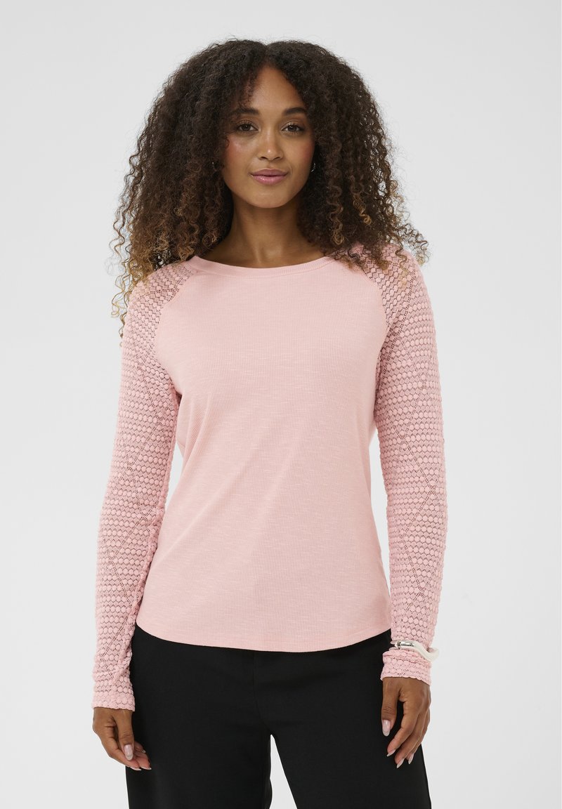 Roze top met lange mouwen en textuur gebreide mouwen. Heeft een ronde halslijn en een geribbelde body. De mouwen hebben een geometrisch patroon.