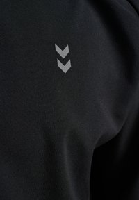 Zwei graue nach unten zeigende Chevron-Symbole auf einem schwarzen, strukturierten Stoffhintergrund.