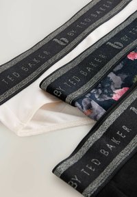 Three pairs of socks in white, black, and a floral pattern. Each features a textured waistband with "Ted Baker" printed in silver.