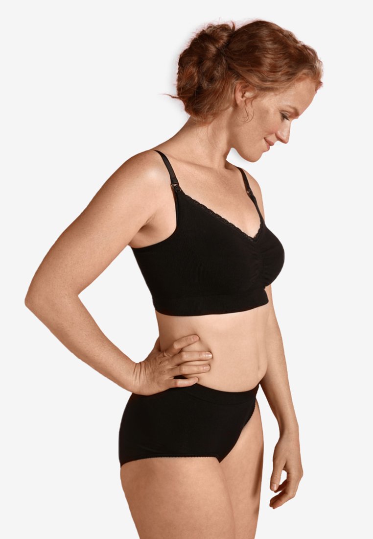 Sujetador negro de canalé con encaje y tirantes ajustables, combinado con unas braguitas negras de talle alto a juego, exhibido en una modelo.