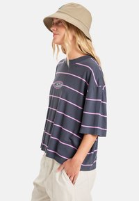 T-shirt oversize bleu marine avec des rayures horizontales roses et un petit logo coloré sur la poitrine. Tissu doux, manches courtes, coupe décontractée.