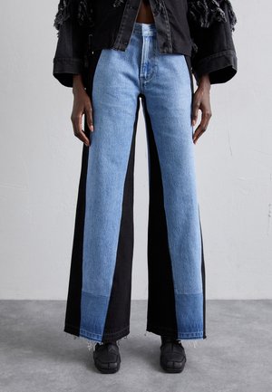 Levikset, joissa on väriblokkimuotoilu kahdessa eri sinisen deniminsävyssä ja mustassa, frayed-hapsuilla ja korkean vyötärön leikkauksella.