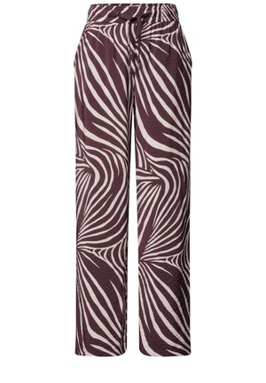 Nærbillede af en person iført lilla og hvide zebra-mønstrede bukser med snøre i taljen og en hvid indstoppet top.