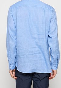 Camicia a maniche lunghe azzurro chiaro in lino, con colletto a camicia, taglio dritto e dettagli con bottoni sui polsini.