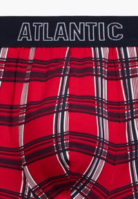 Czerwone bokserki w kratkę z granatowym elastycznym pasem, na którym widnieje napis "ATLANTIC". Wzór składa się z białych i czarnych linii splecionych ze sobą.