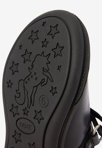 Schwarze Gummisohle mit einem Einhornmotiv und Sternmustern, mit der eingeprägten Zahl "6" und einer glatten Oberfläche.