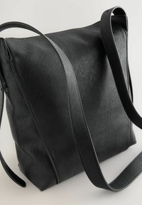 Borsa a spalla in pelle sintetica nera con texture liscia, forma rettangolare piatta e tracolla regolabile. Presenta un dettaglio delle cuciture discreto.