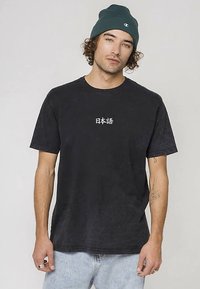 Mustast puuvillast lühikeste varrukatega ja ümara kaelusega t-särk. Esiküljel on valged Jaapani tähed, kombineeritud helesiniste teksadega.