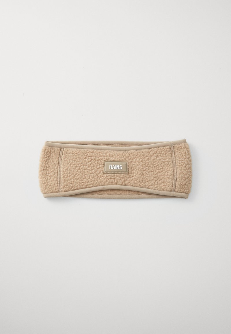 Beige fleece haarband met een rechthoekig "RAINS" label in het midden op een effen witte achtergrond.