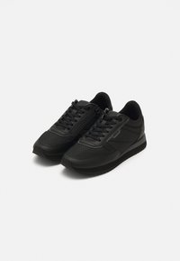 Paire de baskets noires à lacets avec fermeture éclair latérale et semelle en caoutchouc, présentée sur fond blanc.