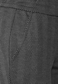 Tessuto con motivo a righe bianche e nere con design a zigzag. Presenta una finitura strutturata e pieghe lungo i lati.