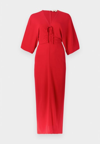 Sarkanā kleita ar īsām piedurknēm, V veida izgriezumu un centrālu kroku detaļu. Gluda auduma ar taisnu piegriezumu. Aizmugurē rāvējslēdzēja aizdare un kleitas garums līdz potītēm.