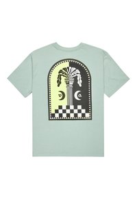 Camiseta verde menta con un gráfico en forma de arco que presenta un jarrón, hojas texturizadas y un patrón de tablero de ajedrez en blanco y negro.