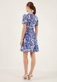 Rochie scurtă cu un model albastru și alb, cu mâneci scurte, talie ajustată și fustă evazată. Textură netedă și lungime până la mijlocul coapsei.