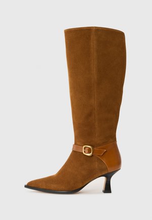Stivale marrone in suede alto fino al ginocchio, con punta affusolata, una fascia in pelle marrone a contrasto e dettaglio con fibbia dorata, e un tacco alto e sottile.