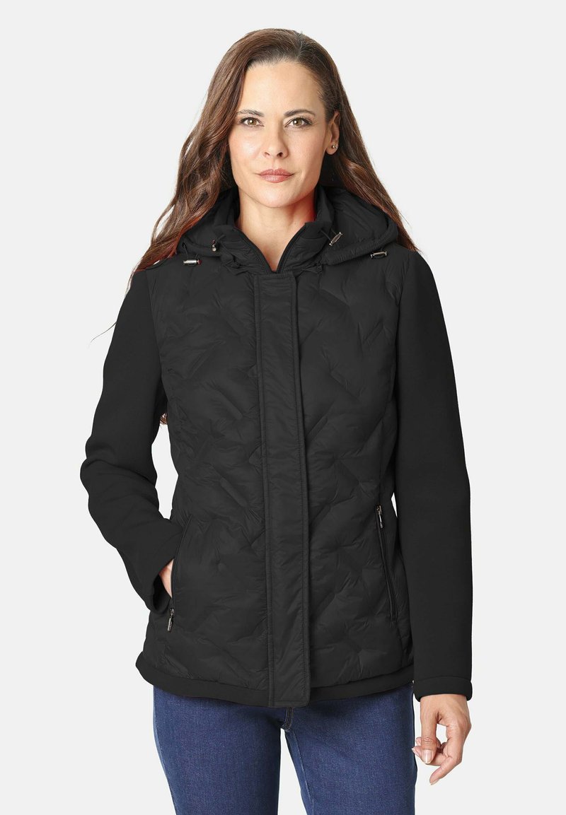 Chaqueta de plumas negra con capucha, que presenta una textura acolchada en el frente y mangas lisas, bolsillos laterales con cremallera y un diseño ajustado.