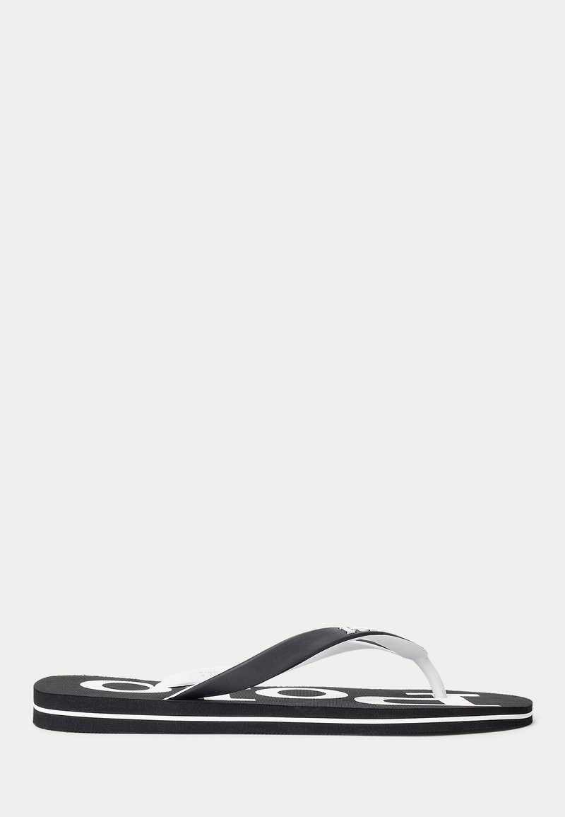 Svart-hvitt flip-flop-sandal med hvit logo tekst på sålen og svarte øvre stropper, vist fra siden mot en ensfarget bakgrunn.