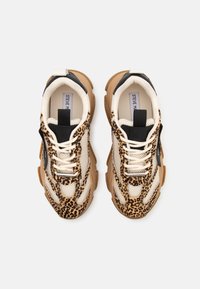 Baskets épaisses avec des accents à imprimé léopard, des panneaux en mesh beige, des languettes de languette noires et des semelles épaisses marron, marquées "Steve Madden" à l'intérieur.