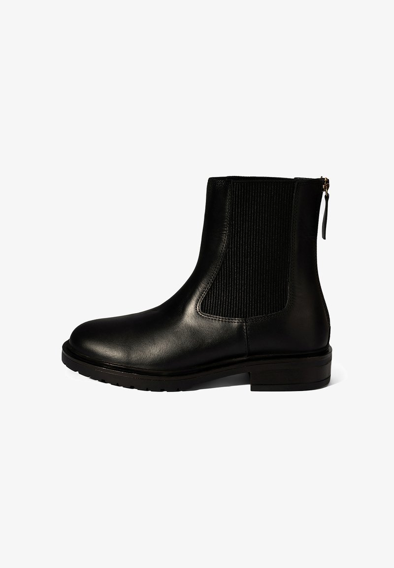 Schwarze Lederstiefelette mit seitlichem elastischem Einsatz, flachem Absatz und Reißverschluss mit Zuglasche, von der Außenseite auf weißem Hintergrund gezeigt.