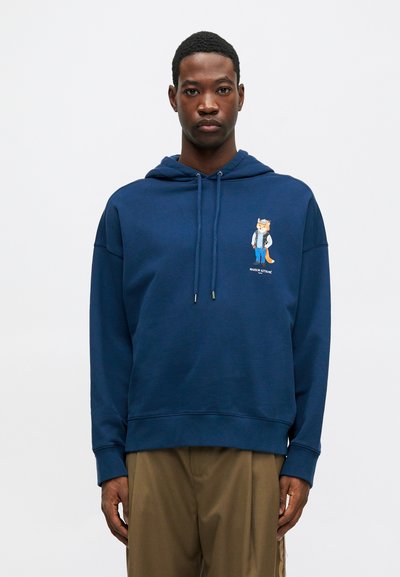 Sudadera azul marino de corte holgado, con un gráfico de un zorro vestido con un conjunto de denim en el pecho, capucha con cordón ajustable y puños acanalados.