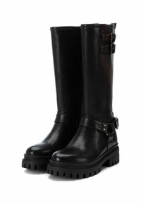 Botas de cuero negro hasta la rodilla con una suela gruesa y texturizada, que incluyen detalles de hebillas plateadas y un acabado suave.