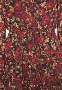 Langes Blumenmaxikleid mit dunklem Hintergrund, das rot, pink und beige Blumen zeigt, eine durchgeknöpfte Front hat und mit einem gebundenen Taillengürtel sowie Rüschenschichten versehen ist.