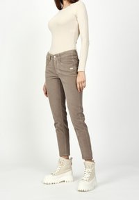 Beige long-sleeve top paired with light brown corduroy pants. Notable details include front pockets and white lace-up boots with thick soles.