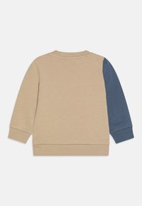 Krátka mikina s okrúhlym výstrihom v béžovej farbe s tmavomodrými rukávmi. Mäkka bavlnená tkanina, rebrované manžety a lem, minimalistický dizajn, bez vzorov alebo grafiky.