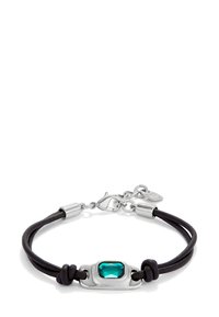 Bracelet en cuir noir avec un fermoir en métal argenté et une pierre précieuse rectangulaire verte au centre, accentuée de détails noués.