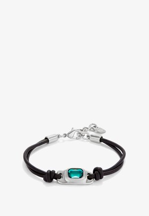 Bracelet en cuir noir avec un fermoir en métal argenté et une pierre précieuse rectangulaire verte au centre, accentuée de détails noués.