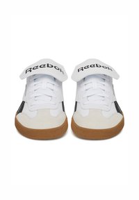 Biele tenisky s čiernymi akcentmi a textúrovanou béžovou špičkou. Velcro pásik nad šnúrkami obsahuje čierne logo Reebok. Gumová podrážka s gripom.