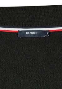 Zwarte trui met een gestructureerde brei, met een label waarop 'HECHTER PARIS' staat en meerkleurige strepen in rood en wit bij de halslijn.