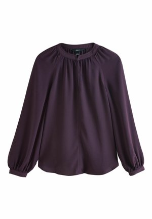Blouse à manches longues violet foncé avec col rond, détails froncés au col et aux poignets, et finition en tissu fluide et lisse.